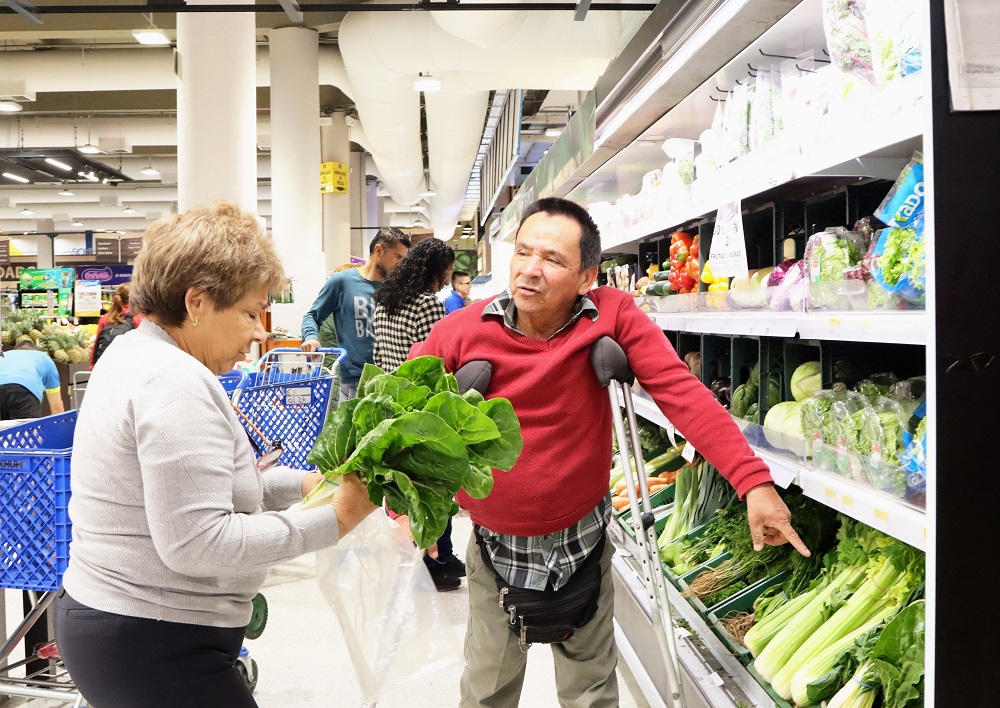 Hombre con muletas es ayudado por una mujer en el supermercado