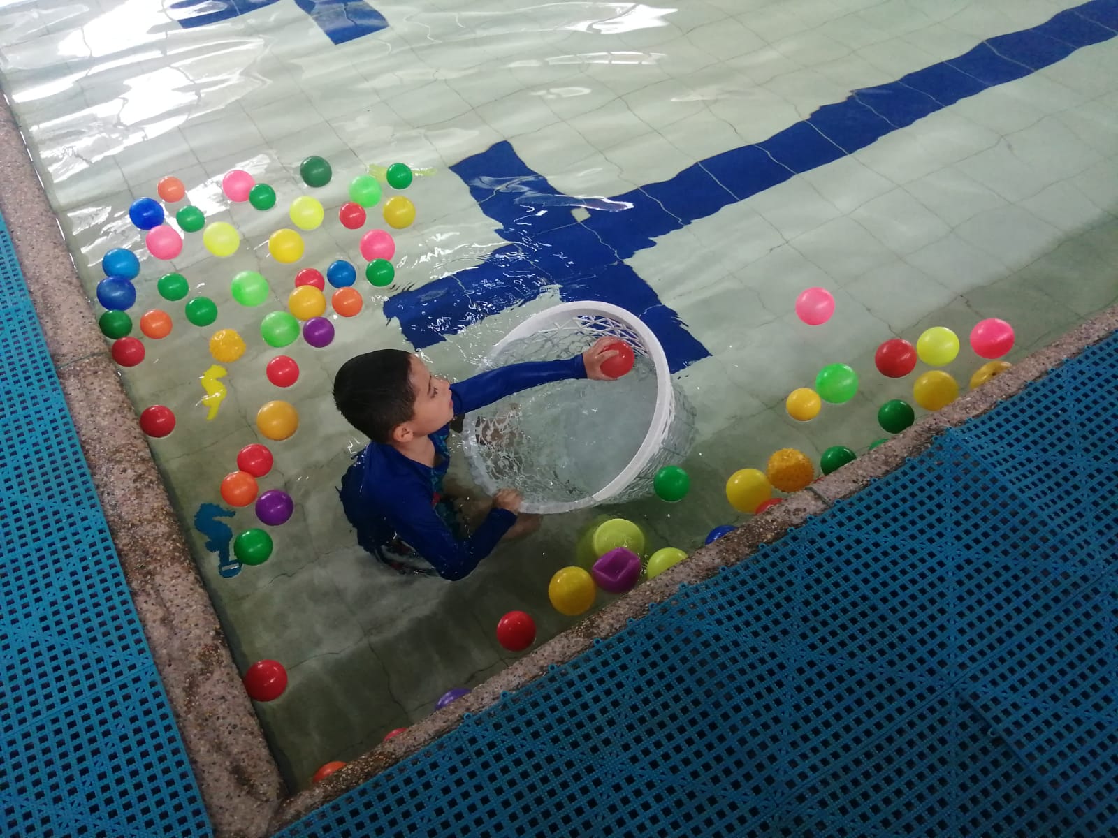 foto de niñojugando en la piscina con pelotas
