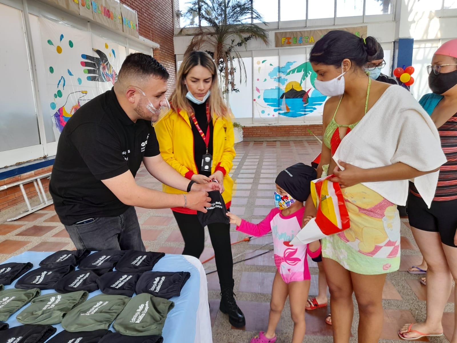 foto de funcionarios entregando gorros de piscina a niños y niñas