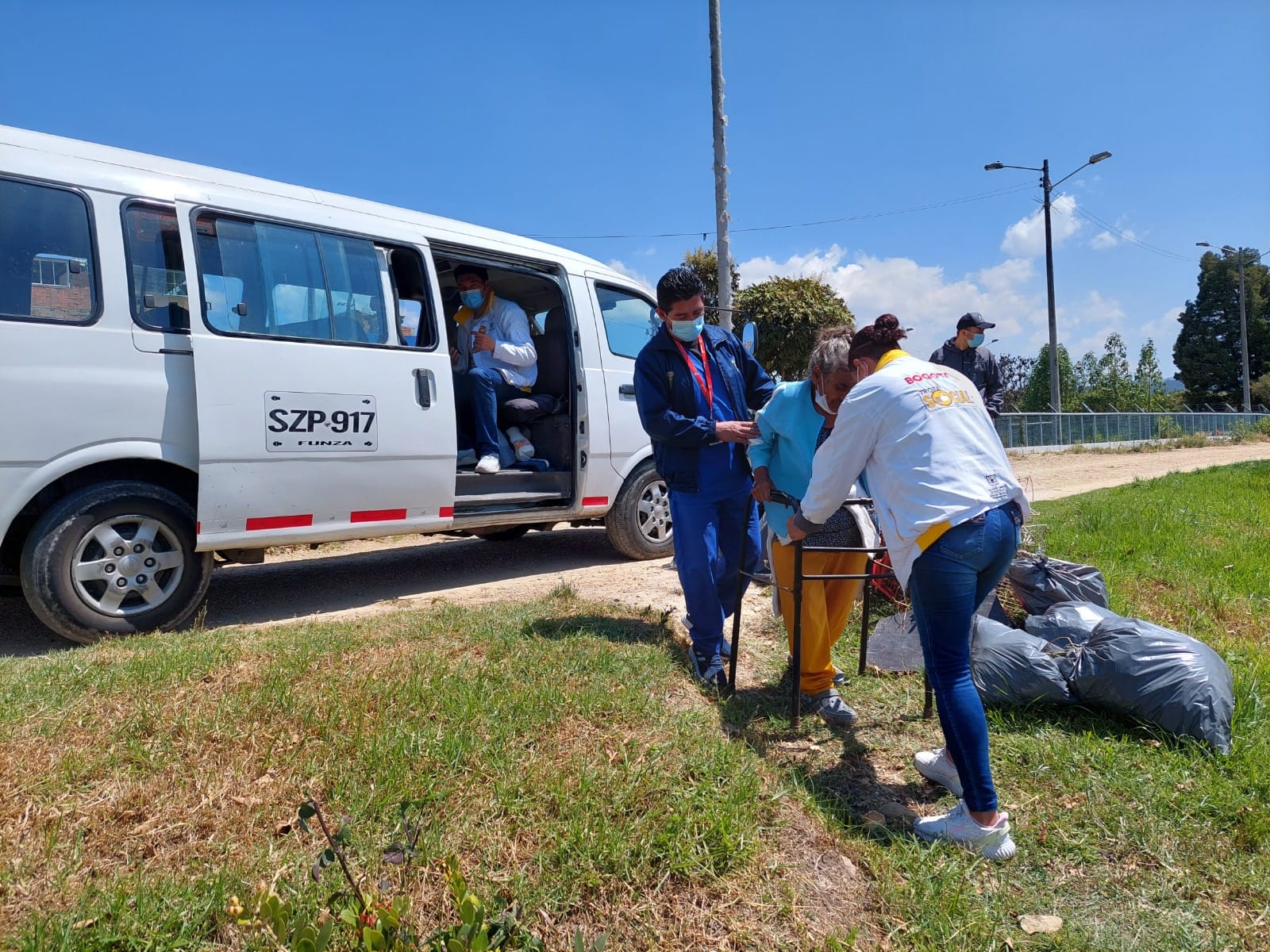 foto de funcionaria ayudando a persona mayor a caminar