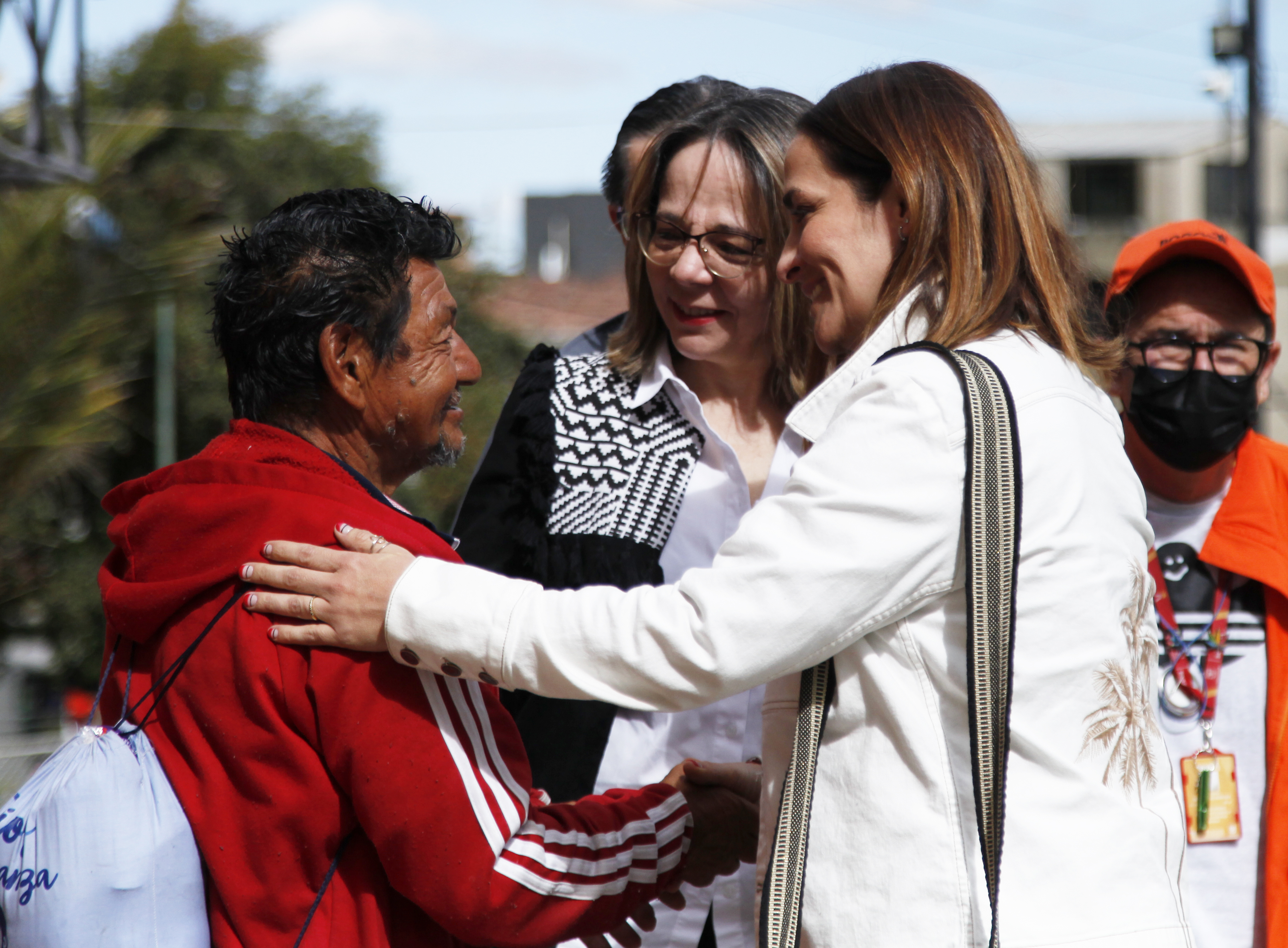 mujeres abrazando habitante de calle