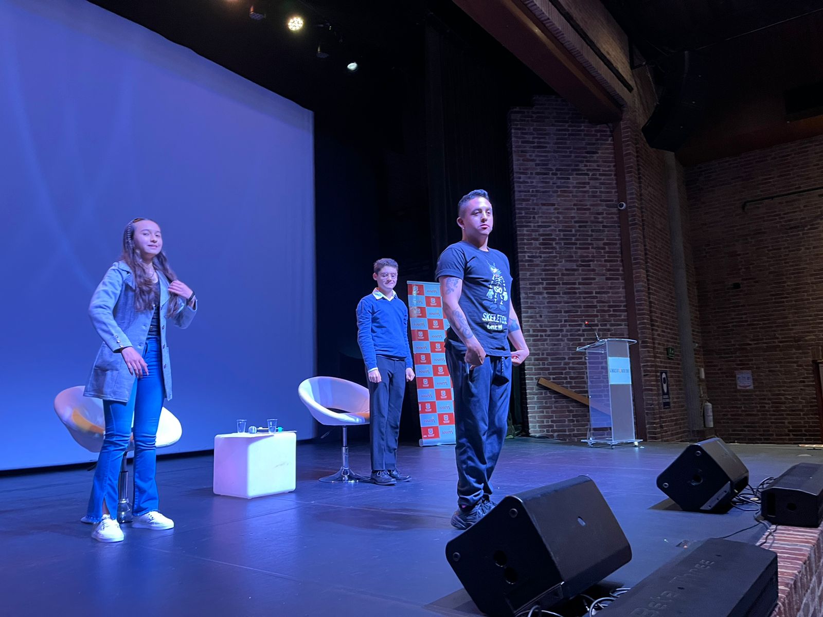 foto de la tarima del auditorio con niño, niña y adulto