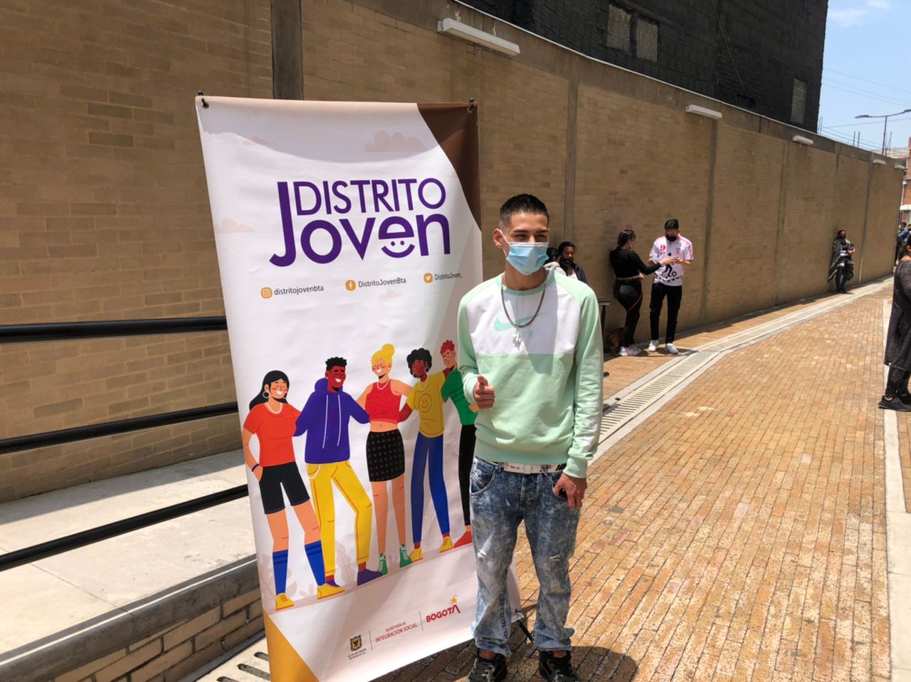 foto de joven al lado de pancarta de distrito joven