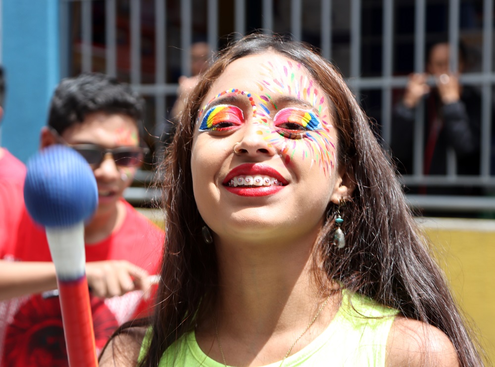 Adolescente femenina maquillada con colores destellantes sonrriendo