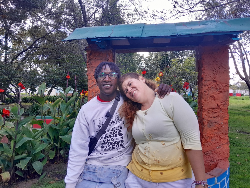 Pareja de hombre y mujer abrazados en un parque mirando de frente felices