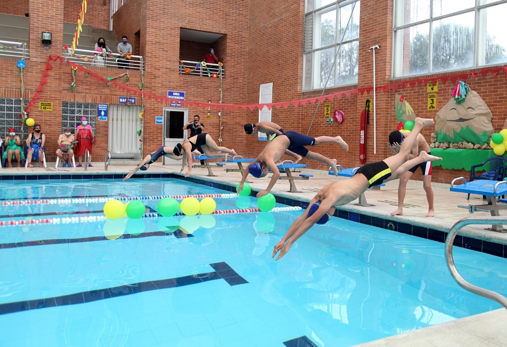 cuatro personas practicando clavados en piscina