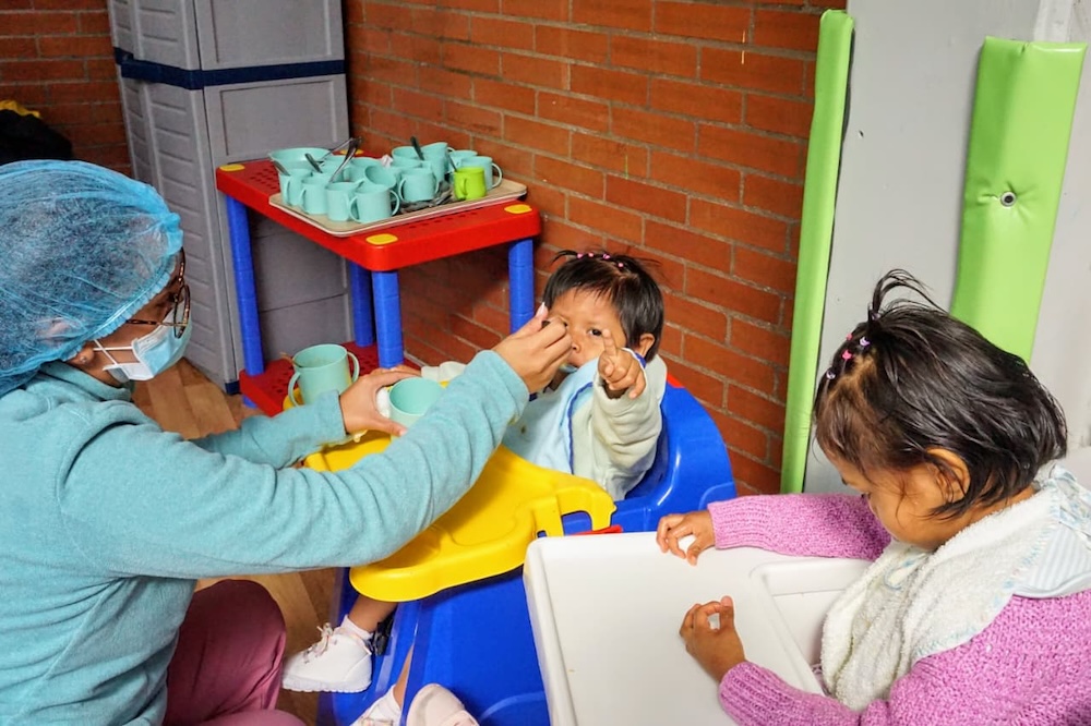 Foto de funcionaria de jardin infantil alimentando a bebes