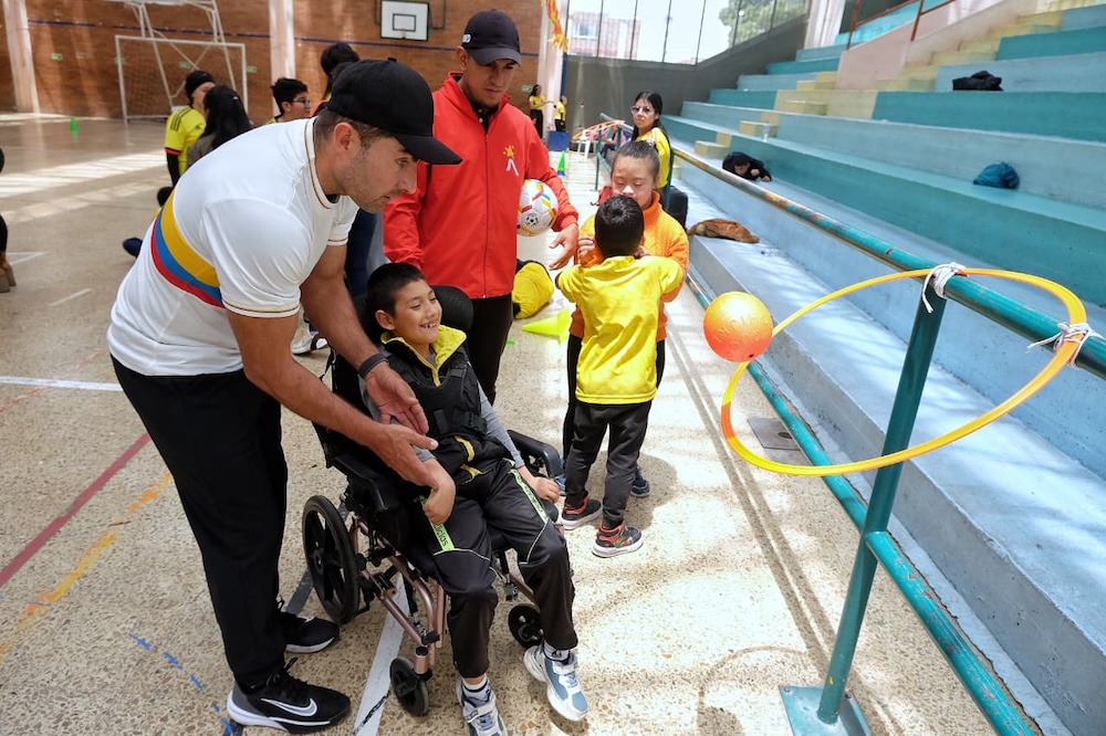 foto de cuidadores ayudando a niño en silla de ruedas a realizar las actividades de las olimpiadas
