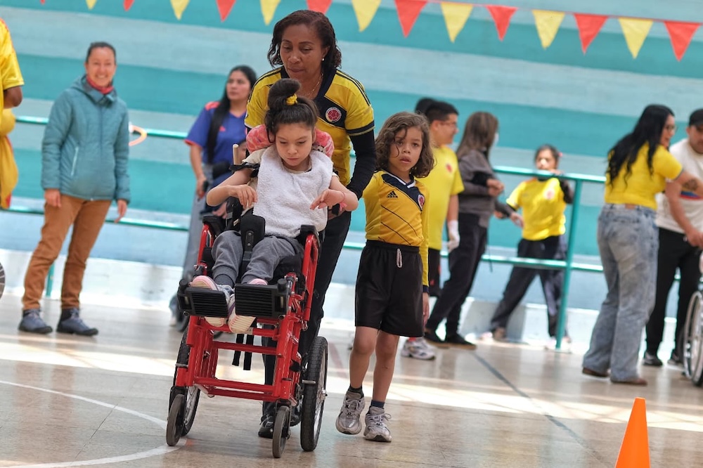 foto mujer llevando a niña en silla de rudas a realizar actividades