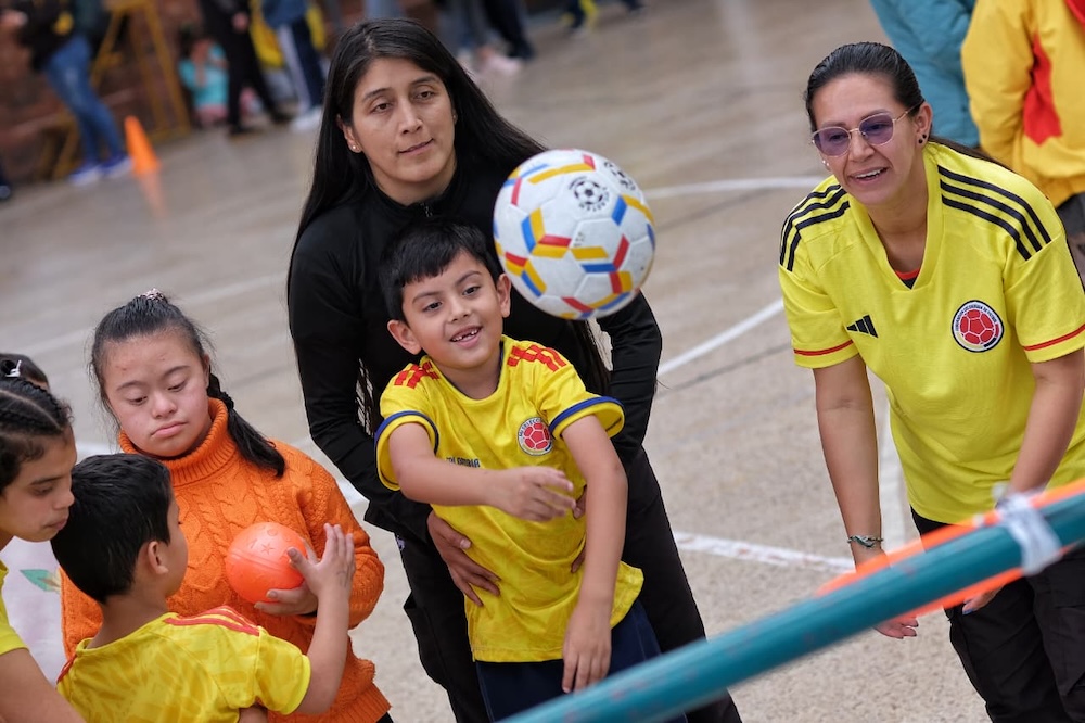 foto de mujer ayudando a niño a lanzar un balon de futbol