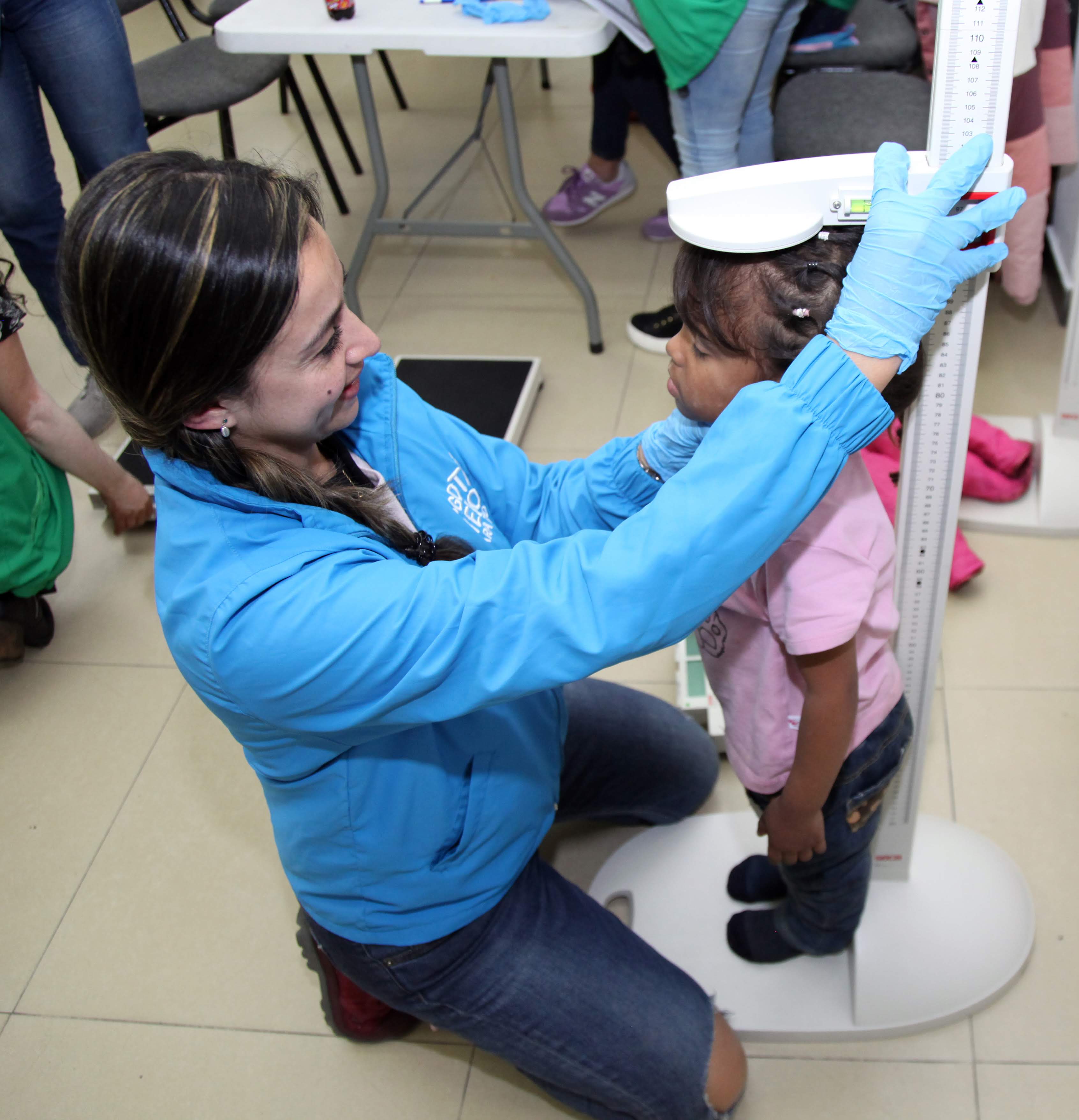 foto de una funcionaria midiendo a un niño