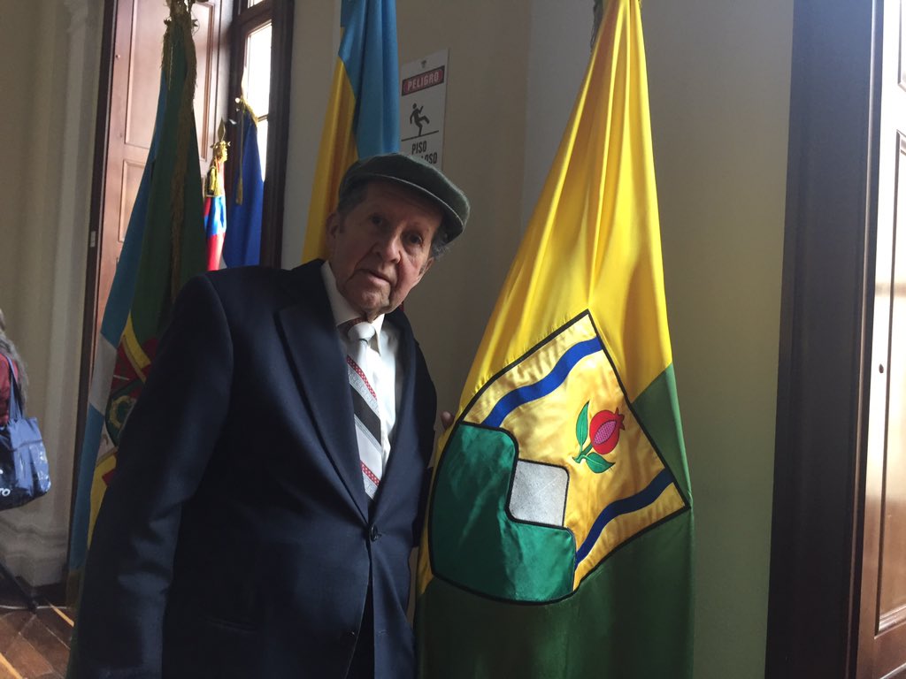 foto de hombre mayor al lado de una bandera